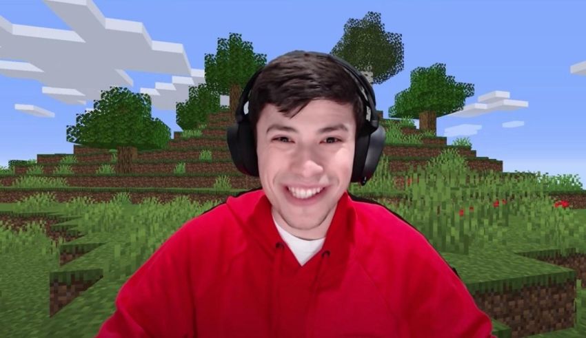 A young man in a red shirt is smiling in front of a minecraft.