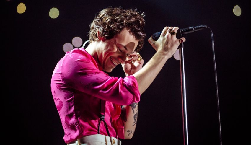 A man in a pink shirt singing into a microphone.