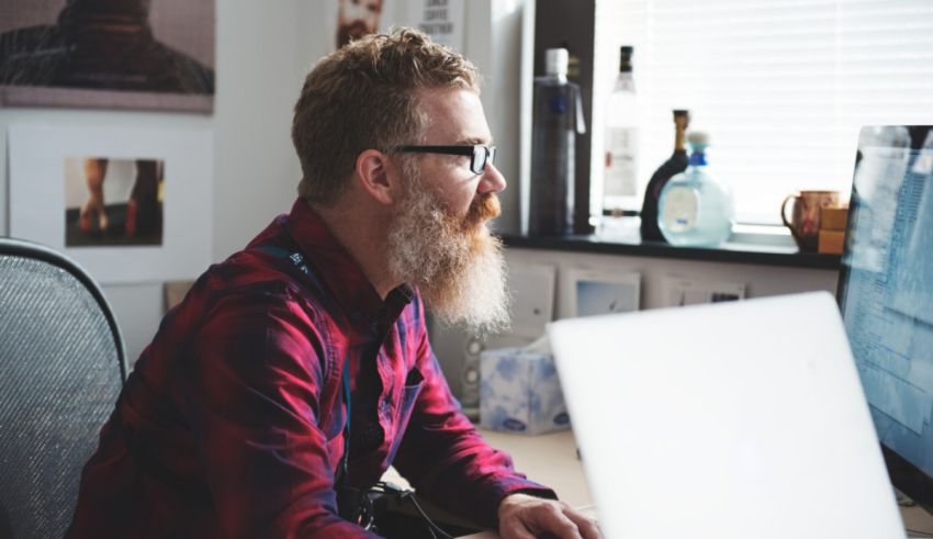 A man with a beard working on a computer.