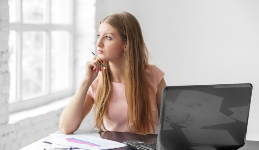 A young woman sitting at a desk with a laptop and papers.