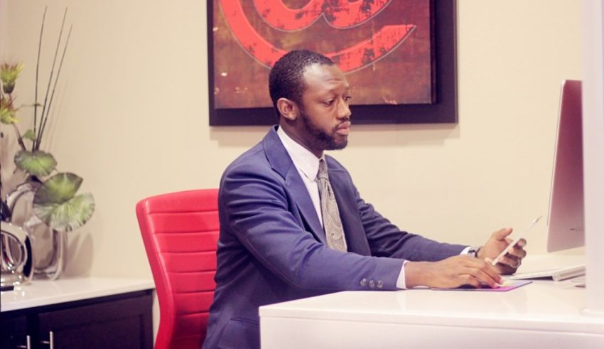 A man in a suit sitting at a desk using a computer.