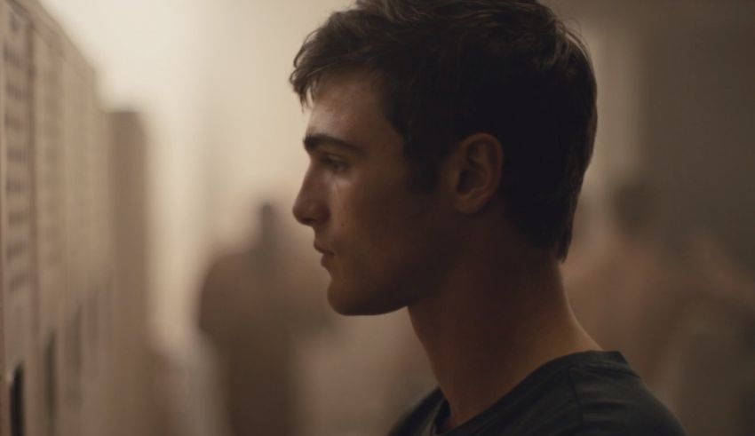 A young man looking at lockers in a locker room.