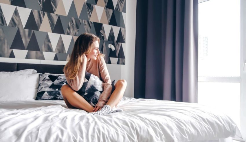 A young woman sitting on a bed in a hotel room.