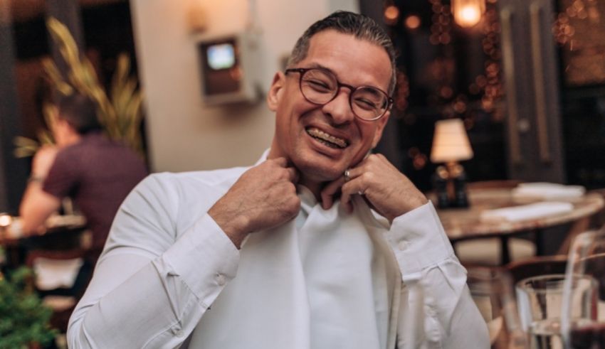 A man in a white shirt is smiling in a restaurant.