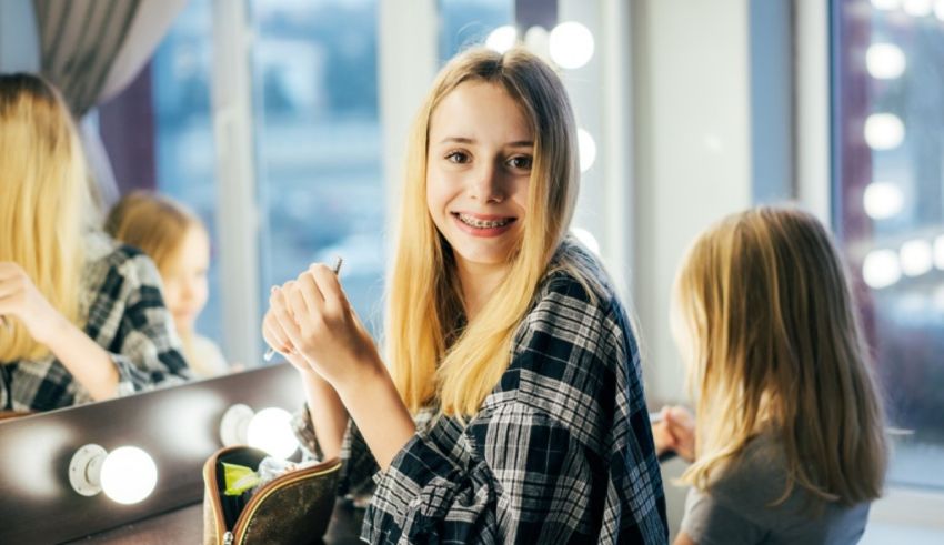 A girl in a plaid shirt is sitting in front of a mirror.
