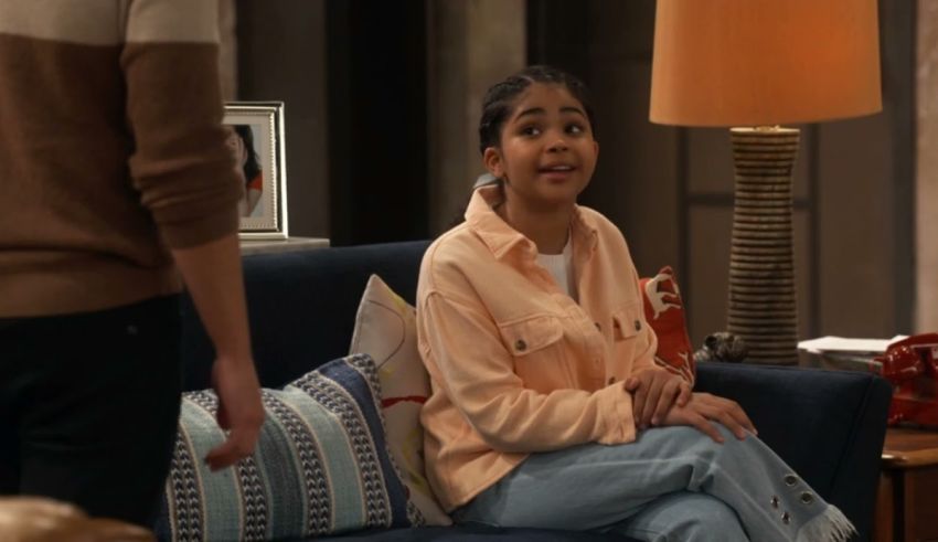 A young girl is sitting on a couch in a living room.