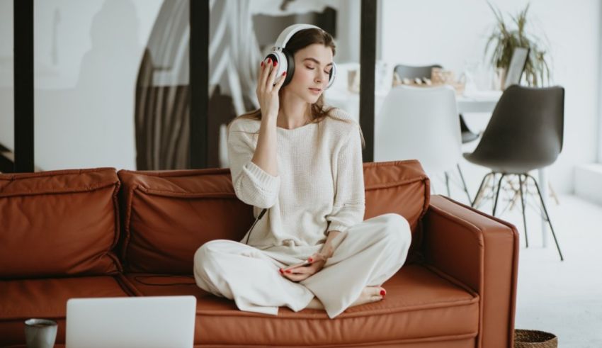 A woman is sitting on a couch listening to music.