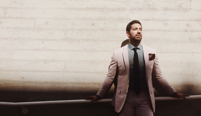 A man in a pink suit leaning against a wall.