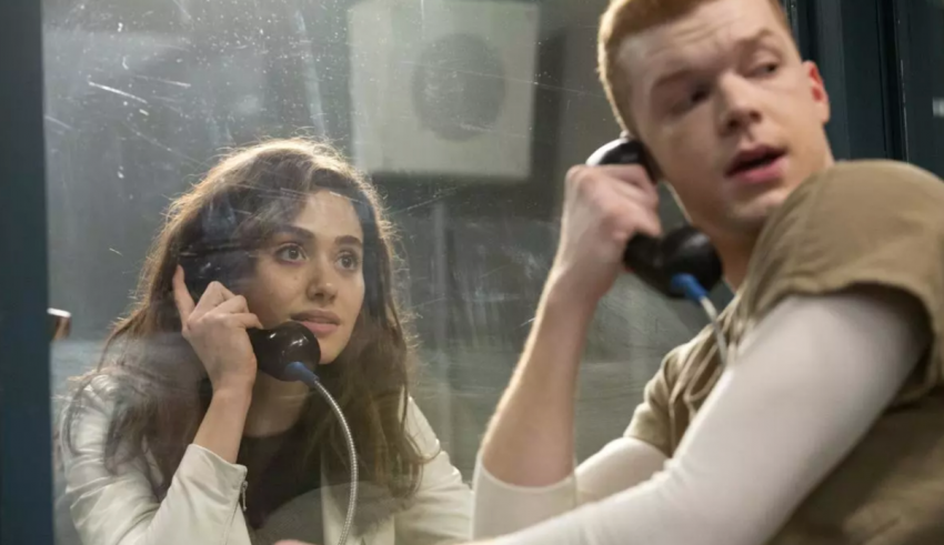 A man and woman talking on the phone in a jail cell.