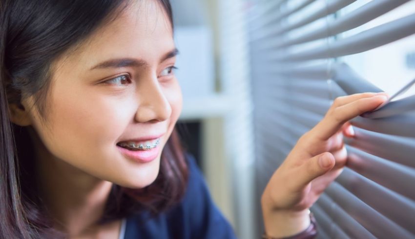 Asian woman looking at blinds in the office.