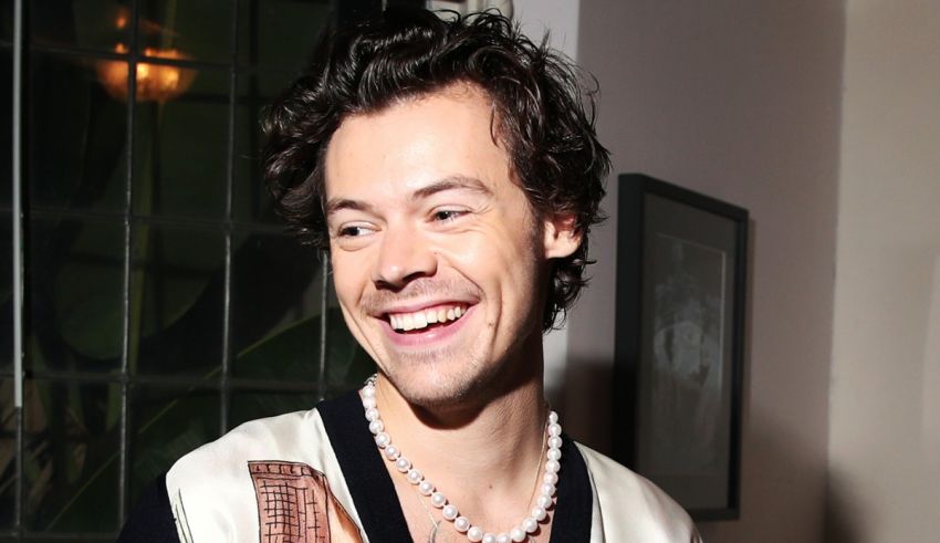 A young man is smiling while wearing a pearl necklace.
