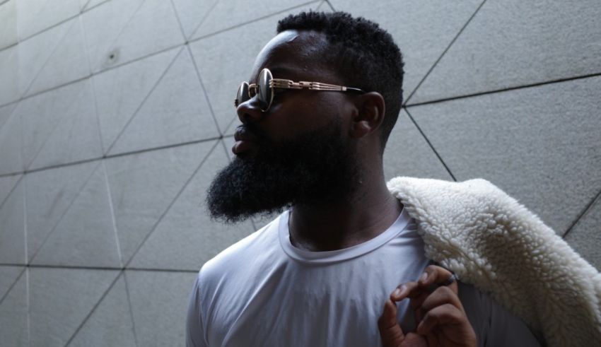 A man with a beard wearing sunglasses and a white shirt.
