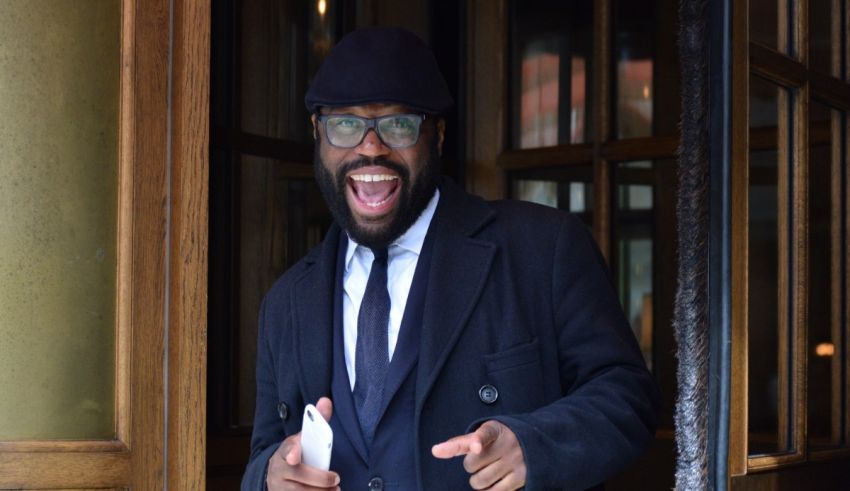 A man in a suit and hat with a smile on his face.