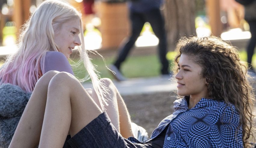 Two young women sitting on the ground in a park.