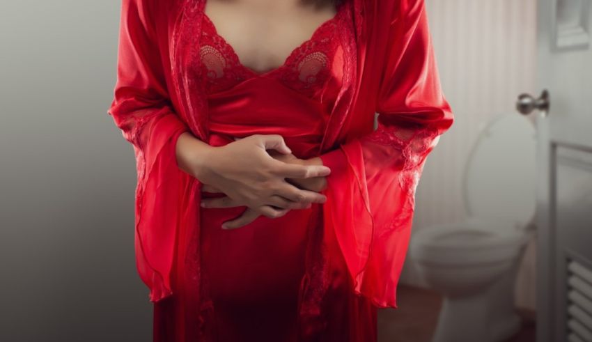 A woman in a red robe standing in front of a toilet.