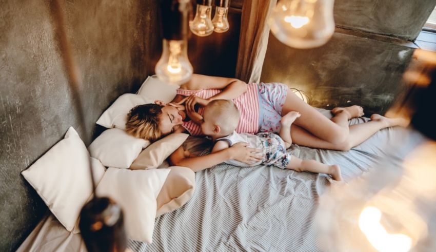 A woman is breastfeeding her baby in a bed with light bulbs.
