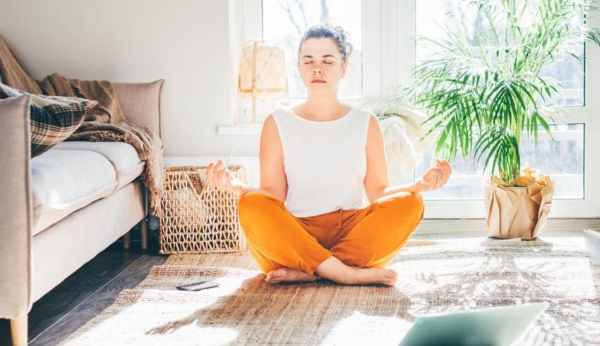 A woman meditating on the floor in front of a window.