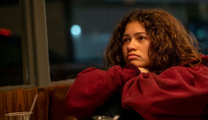 A girl in a red hoodie sitting at a table.