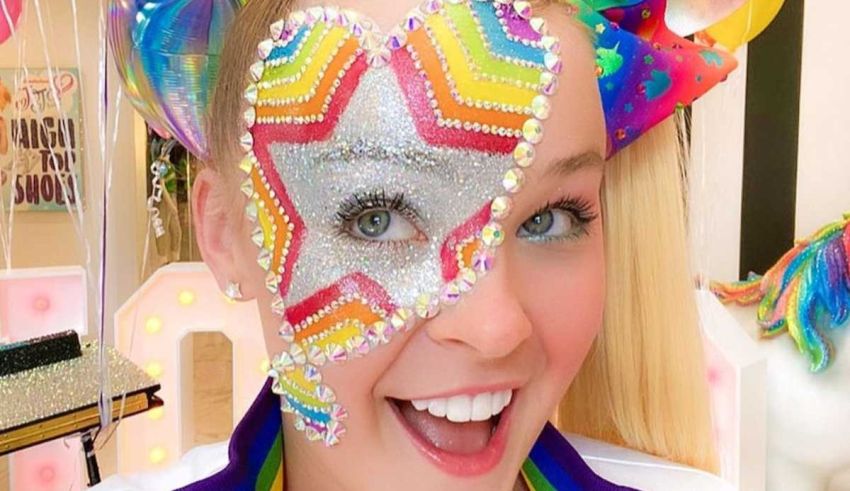 A girl with a rainbow face painted on her face.