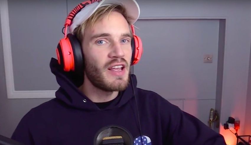 A man in a hoodie with headphones in front of a microphone.