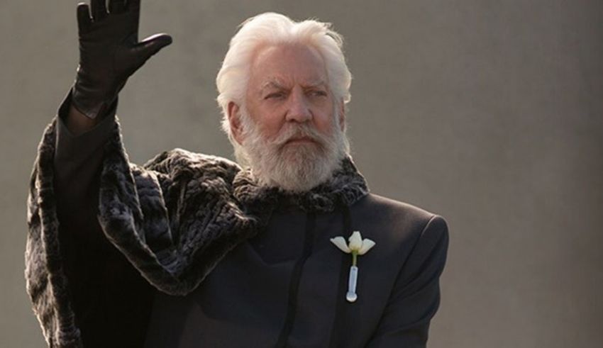 A man in a black suit waving his hand.