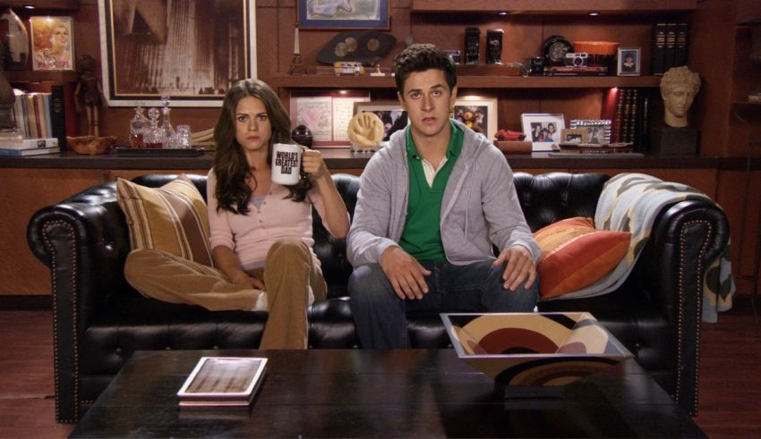 A man and a woman sitting on a black couch.