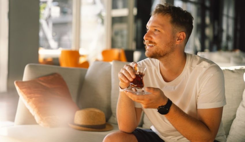 A man sitting on a couch with a drink in his hand.