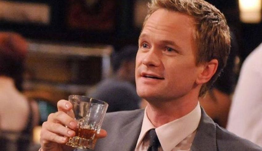 A man in a suit holding a glass of whiskey.