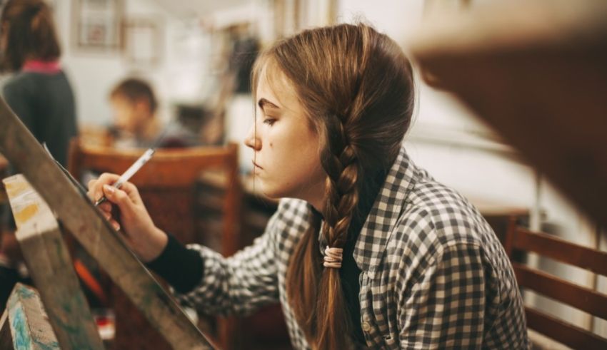 A girl is painting on an easel in an art studio.