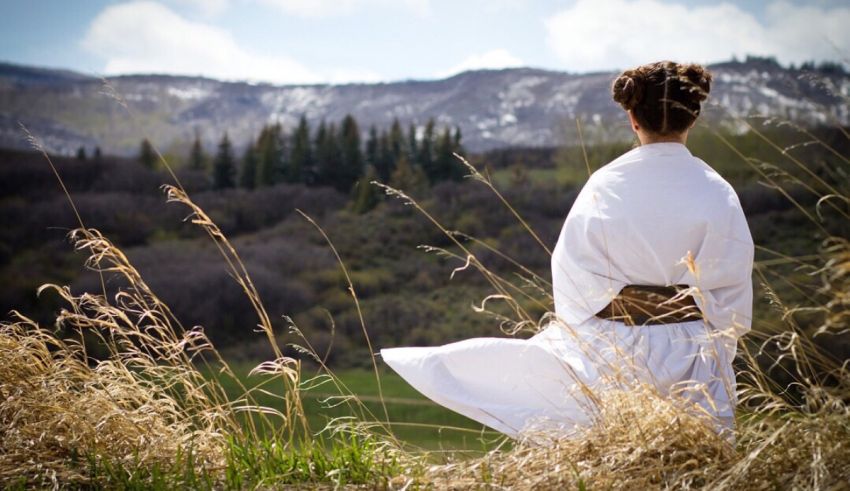A woman in a white robe is standing in a field.