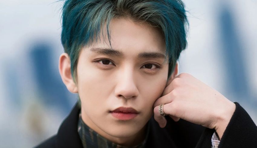A young man with blue hair is posing for a photo.