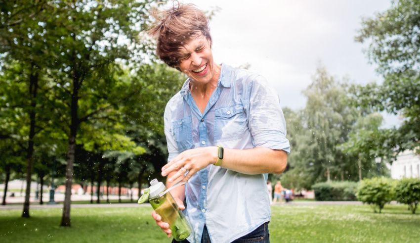 A young man holding a water bottle in a park.