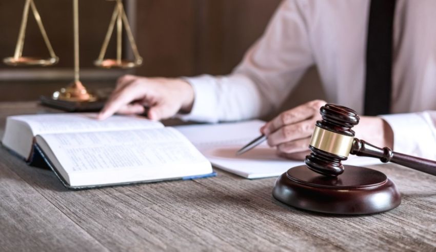 A man in a suit is writing on a book with a gavel.