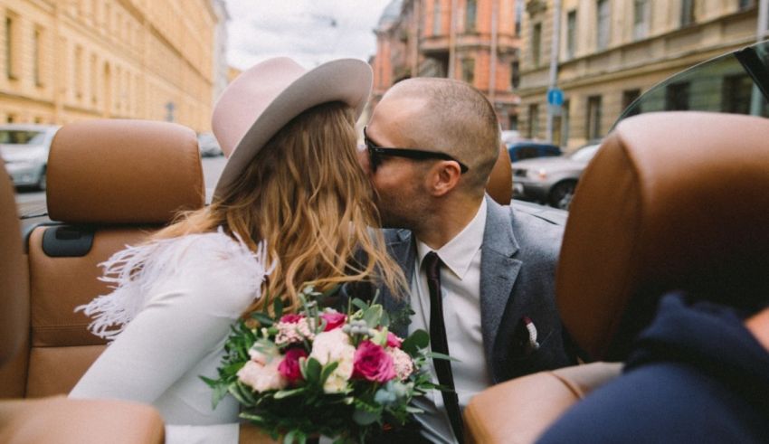 A bride and groom kissing in the back seat of a car.