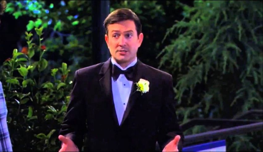 A man in a tuxedo talking to another man.