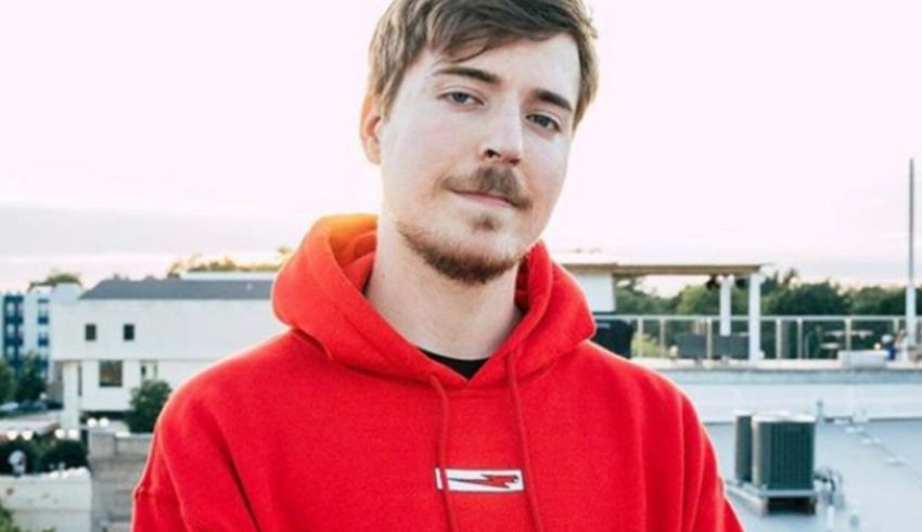 A man in a red hoodie standing in front of a building.