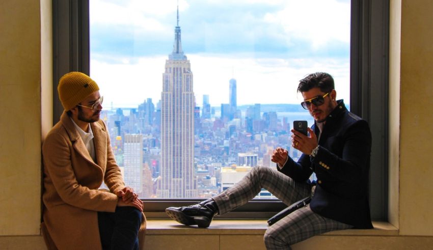 Two men sitting in a window looking at a city.