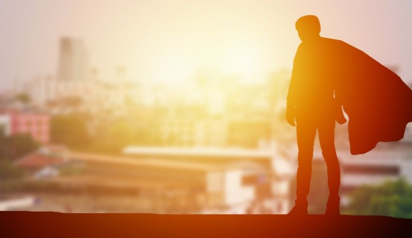 A silhouette of a man with a cape standing on top of a hill.