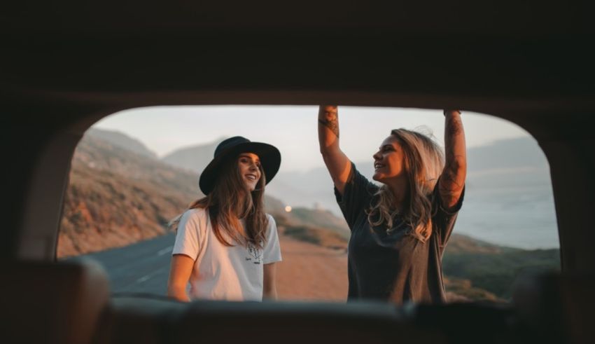 Two women standing in the back seat of a car.