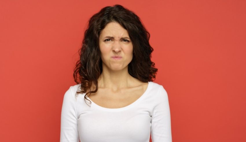 A young woman making a face against a red background.