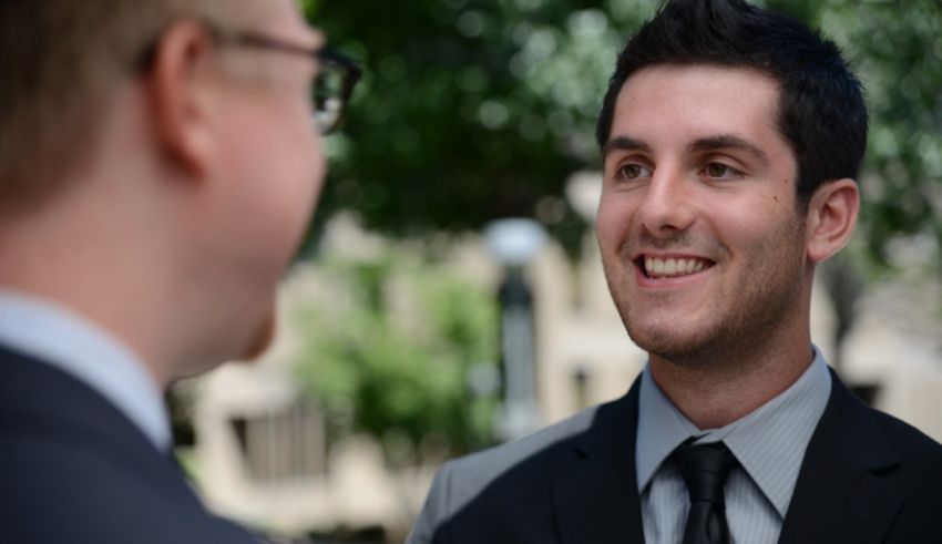 A man in a suit and tie is talking to another man.