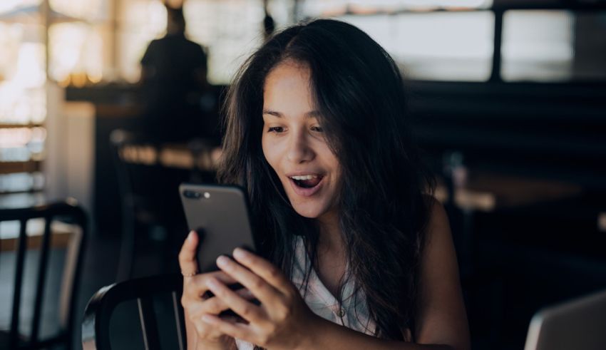 A woman is looking at her phone while sitting in a cafe.