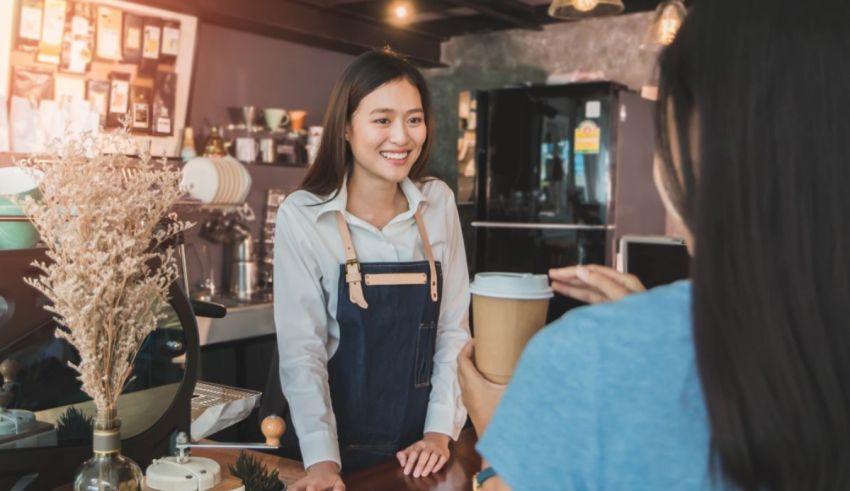 A woman is talking to a customer at a coffee shop.