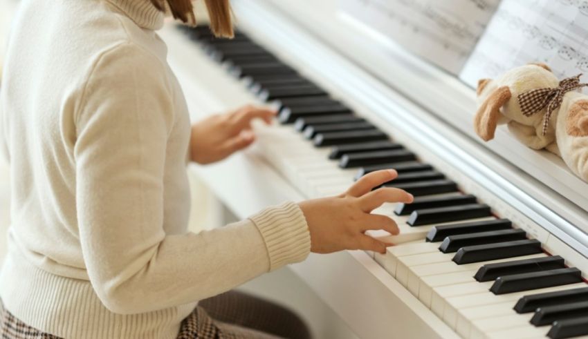 A girl is playing the piano with a teddy bear.