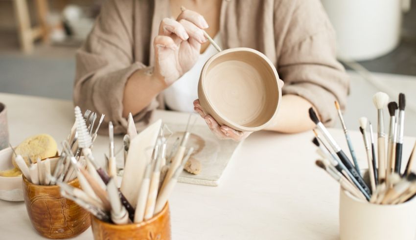 A woman is sitting at a table with a bowl and brushes.