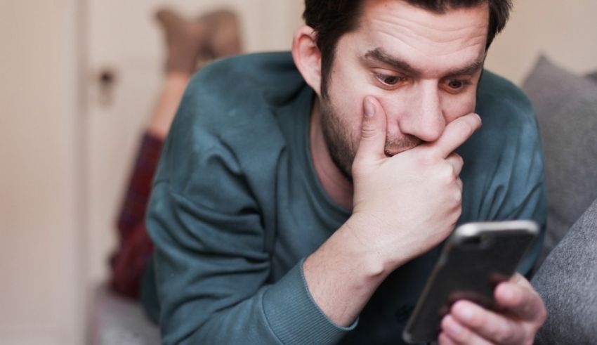 A man laying on the couch looking at his phone.