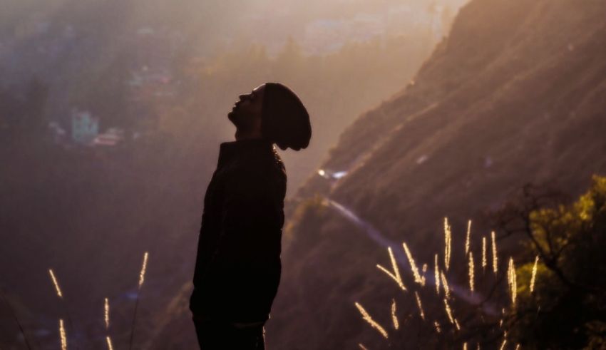 A silhouette of a man standing on top of a hill.