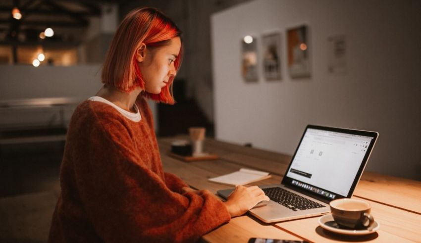 A woman working on a laptop in a dark room.