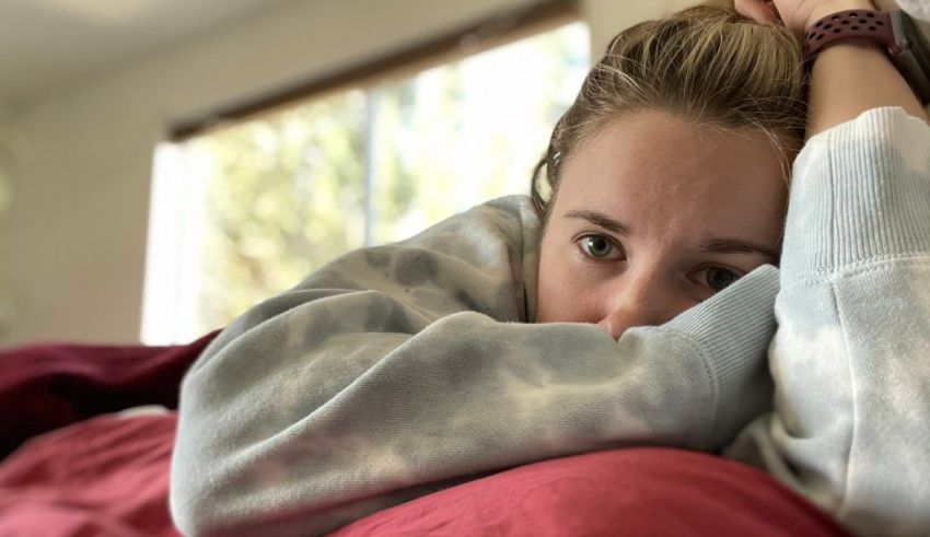 A woman is laying on a bed with her head resting on her hand.