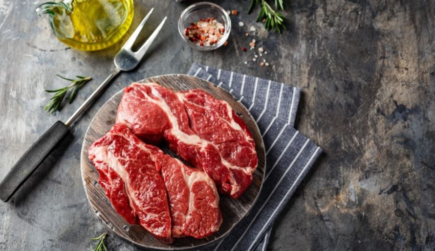 Raw beef on a cutting board with herbs and spices.